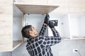 The carpenter sets the door of the kitchen shelves