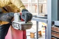 Carpenter is shaving red wood door by his shaving machine in outdoor field with steel pole building structure environment Royalty Free Stock Photo