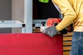 Carpenter is shaving red wood door by his shaving machine in outdoor field with steel pole building structure environment Royalty Free Stock Photo