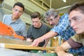 Carpenter showing apprentices how to use machinery Royalty Free Stock Photo