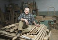 Carpenter Sitting on Wood Stacked in Workshop Royalty Free Stock Photo