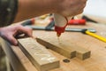 Carpenter squeezing glue onto two pieces of wood with one hand. Woodworking process closeup. Workshop table with tools