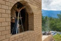 A carpenter on a step ladder grinding an adobe brick frame to accommodate a window