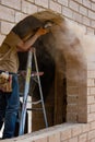 A carpenter on a step ladder grinding an adobe brick frame to accommodate a window Royalty Free Stock Photo