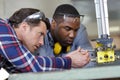 Carpenter teaching apprentice how to cut wood