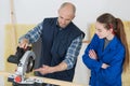 Carpenter training female to use mechanized saw