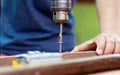 The carpenter uses a drill to tighten the screws to the plank