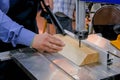 Carpenter using bandsaw tool, cutting piece of wood at workshop - close up