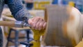 Carpenter using chisel for shaping wood piece on lathe - side view