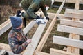 Carpenter using circular saw for cutting joist for building wooden frame house. Royalty Free Stock Photo