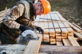 Carpenter using circular saw for cutting joist for building wooden frame house.