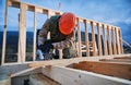 Carpenter using circular saw for cutting joist for building wooden frame house. Royalty Free Stock Photo