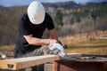 Carpenter using circular saw for cutting joist for building wooden frame house.