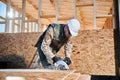 Carpenter using circular saw for cutting OSB board for building wooden frame house. Royalty Free Stock Photo