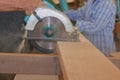 Carpenter using circular saw cutting wooden board in wood workshop. Royalty Free Stock Photo