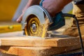 Carpenter using circular saw for cutting wooden boards with hand power tools. Royalty Free Stock Photo