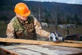 Carpenter using circular saw for cutting joist for building wooden frame house. Royalty Free Stock Photo