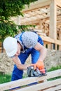 Carpenter using circular saw for cutting wooden plank while building wooden frame house. Royalty Free Stock Photo