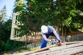 Carpenter using circular saw for cutting wooden plank while building wooden frame house. Royalty Free Stock Photo