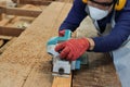 Carpenter using electric planer with wooden plank in carpentry workshop. He is wearing safety equipment Royalty Free Stock Photo