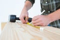 Carpenter using measure tape to mark on plank Royalty Free Stock Photo