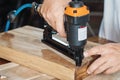 carpenter using nail gun or brad nailer tool on wood box in a workshop ,furniture restoration woodworking concept. selective focus