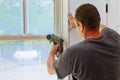 Carpenter using nail gun to moldings on windows, framing trim,