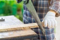 The carpenter ware white gloves use hand saw cutting wood board Royalty Free Stock Photo