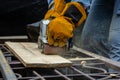 Carpenter wearing gloves and sanding wooden board with handheld belt sander