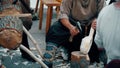 Carpenter wearing traditional costume hews wooden bailer with a hatchet