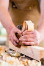 Carpenter with wood planer and workpiece in carpentry Royalty Free Stock Photo