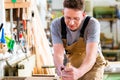 Carpenter with wood planer and workpiece in carpentry Royalty Free Stock Photo