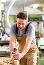 Carpenter with wood planer and workpiece in carpentry Royalty Free Stock Photo