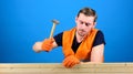 Carpenter, woodworker on busy face hammering nail into wooden board. Man, labourer, handyman in bright vest and gloves Royalty Free Stock Photo