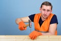 Carpenter, woodworker on calm face hammering nail into wooden board. Handyman concept. Man, handyman in uniform and Royalty Free Stock Photo