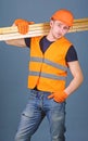 Carpenter, woodworker, labourer, builder on confident face carries wooden beams on shoulder. Man in helmet, hard hat and