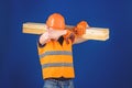 Carpenter, woodworker, labourer, builder on tired face carries wooden beam on shoulder. Tired labourer concept. Man in