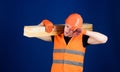 Carpenter, woodworker, labourer, builder on tired face carries wooden beam on shoulder. Man in helmet and protective