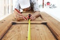 Carpenter at work measures with the tape measure and pencil on w