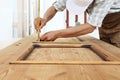 Carpenter work the wood, measuring a thickness with angle square