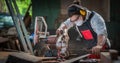 Carpenter work in wood workshop cutting wood piece with circular saw Royalty Free Stock Photo