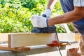 Carpenter working with electric planer on wooden plank Royalty Free Stock Photo