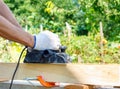 Carpenter working with electric planer on wooden plank Royalty Free Stock Photo