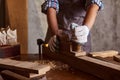 Female Apprentice Planing Wood In Carpentry Workshop. Carpenter woman working with plane Royalty Free Stock Photo