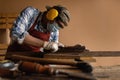 Carpenter working hard while planing on wood with a manual wood planer or plane tool in wood workshop or carpentry workplace, Royalty Free Stock Photo