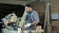 Carpenter working on his craft in a dusty workshop and speak phone. Royalty Free Stock Photo