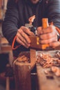 Carpenter working with jointer planing wood plank at workshop, carpenter working with plane on wooden background