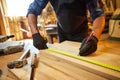 Carpenter working with a wood, marking plank with a pencil and taking measurements to cut a piece of wood to make a piece of Royalty Free Stock Photo