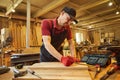 Carpenter working with a wood, marking plank with a pencil and taking measurements to cut a piece of wood to make a piece of Royalty Free Stock Photo