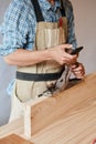 Carpenter working with wood using plane against white wall in studio. Royalty Free Stock Photo